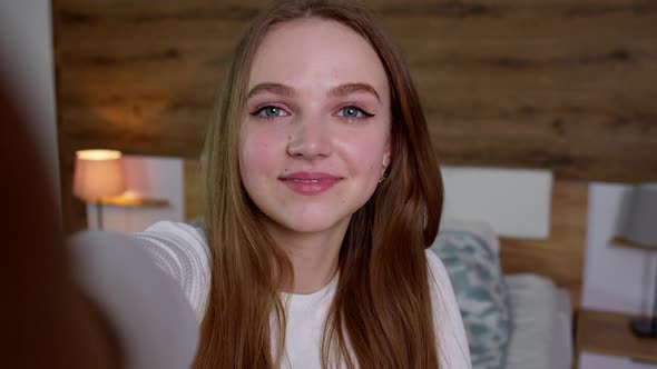 POV Shot of Young Smiling Woman Blogger Makes Selfie on Smartphone for Social Media Networks at Home alt