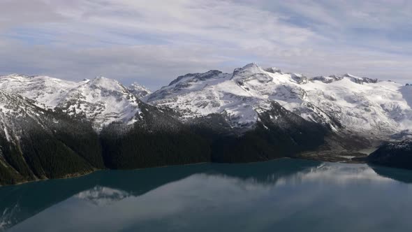 White snowy mountains of Whistler, Canada by the cool calm lake -aerial alt