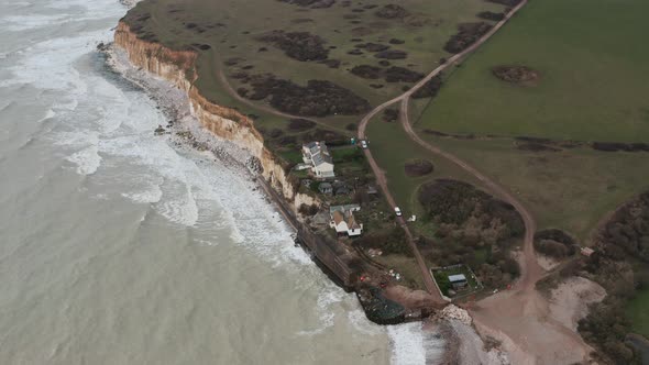 Rotating drone shot of small cottages on white chalk cliffs south England alt