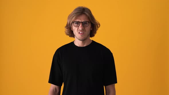 Displeased blond man looking at the camera and giving negative answer alt