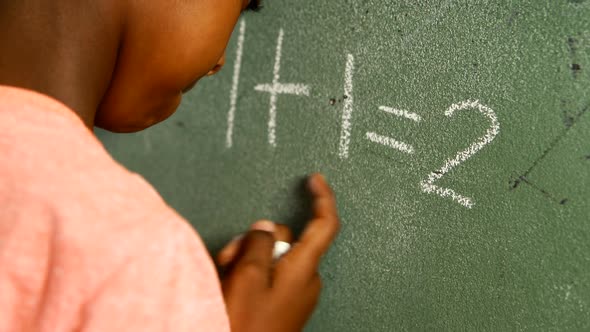 Schoolboy doing mathematics on chalkboard in classroom 4k alt
