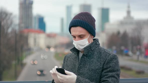 Coronavirus Pandemic: Man in Medical Mask and Gloves Uses App on Smartphone