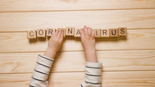 Quarantine. Baby Hands Touching Wood Cubes with Made Word Coronavirus. Child Plays with Word