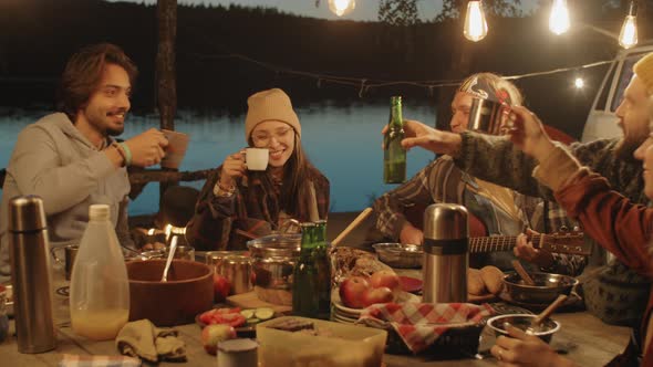 Friends Playing Guitar and Drinking at Camping Dinner alt