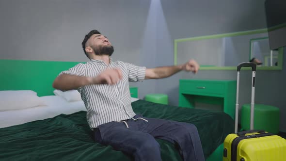 Joyful Carefree Tourist Falling Back on Comfortable Bed in Hotel Room alt