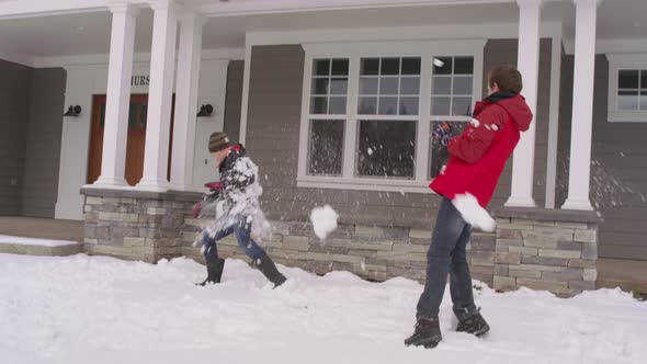 Boys having snow ball fight by home in winter