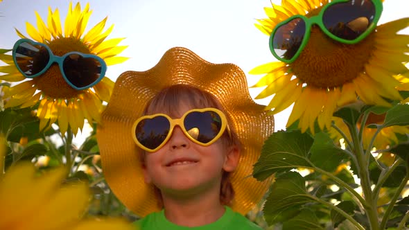 Happy child having fun in spring field of sunflowers, Slow motion