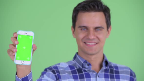 Face of Happy Young Handsome Hipster Man Showing Phone alt
