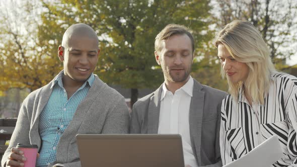 Group of Businesspeople Using Laptop at the Park alt