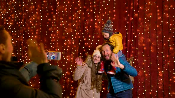 Mother taking photo of family at Christmas market on the night. alt