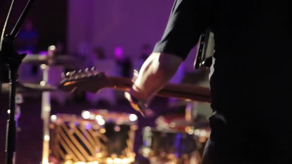 The Musician Plays the Bass Guitar on Stage in a Restaurant