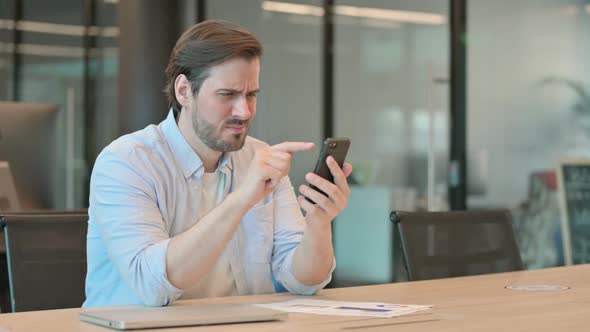Mature Adult Man Reacting to Loss on Smartphone in Office alt