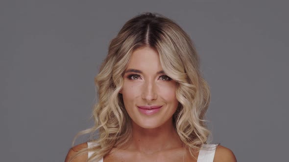 Studio portrait of young and beautiful blond woman over grey background. alt