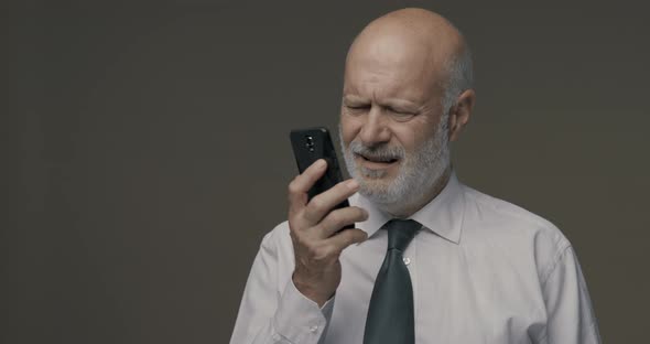 Middle-aged man having difficulties and problems using his smartphone