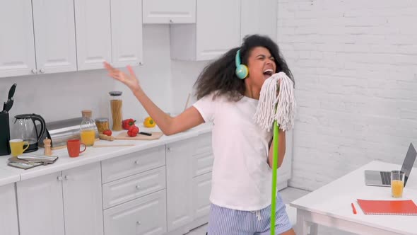 Woman Holding Mop Like a Microphone, Singing and Dancing. 