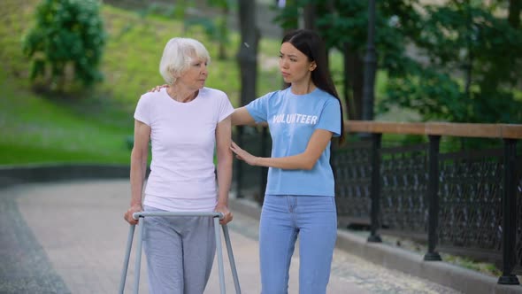 Female Volunteer Supporting Sick Old Woman Walking Frame, Rehab Difficulties alt