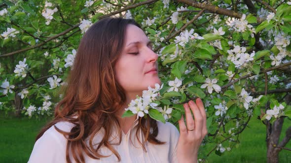 Pregnant woman with apple tree flowers in spring nature. Happiness of pregnancy in blooming nature