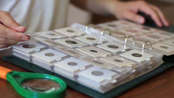 Man Examining Collection Of Coins In Album