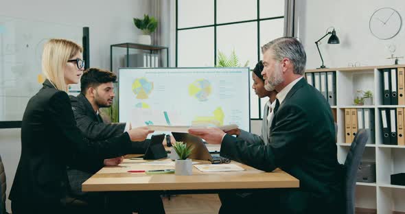 Business Colleagues Working with Financial Reports with Charts During Joint Meeting alt