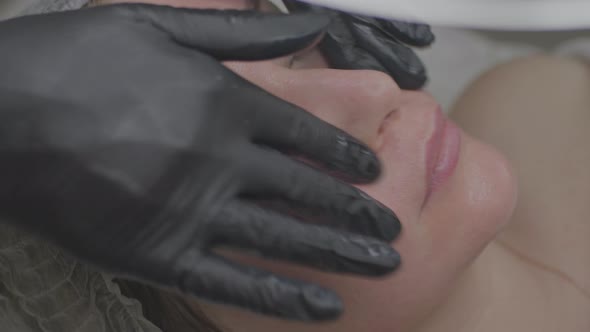 A Woman in a Beauty Salon Applies a Moisturizing Tissue Mask to Her Face alt