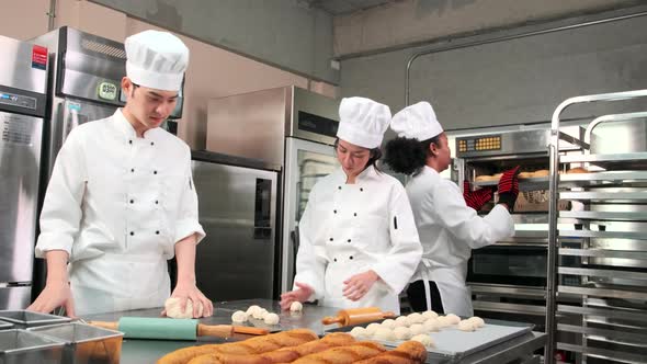 Chefs team in uniforms prepare to bake bread and pastry in stainless kitchen. alt