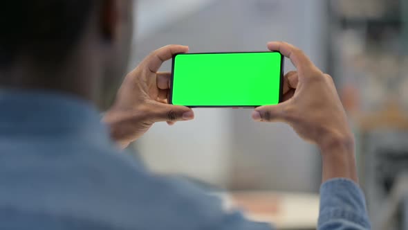African Man Watching Video on Smartphone with Chroma Screen alt
