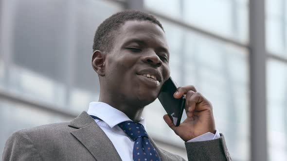 Smiling black american business man talking by phone in the street alt