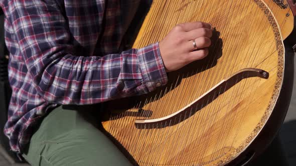 Old ukrainian ethnic musical instrument bandura (pandora) close up. The guy plays outside