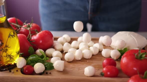 Mozzarella Cheese Small Balls Falling on Wooden Cutting Board alt