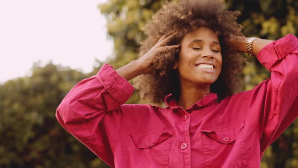 Smiling Young Woman With Afro Hair In Pink Clothes alt