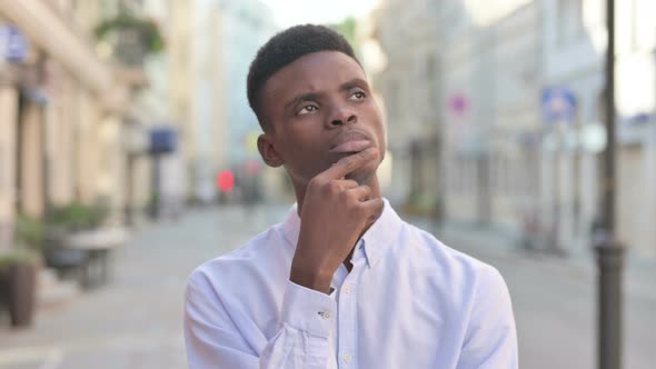 Pensive African Man Thinking While Standing Outdoor alt