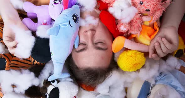 Plump Man Lies in Heap of Plush Toys and Stuffing Closeup