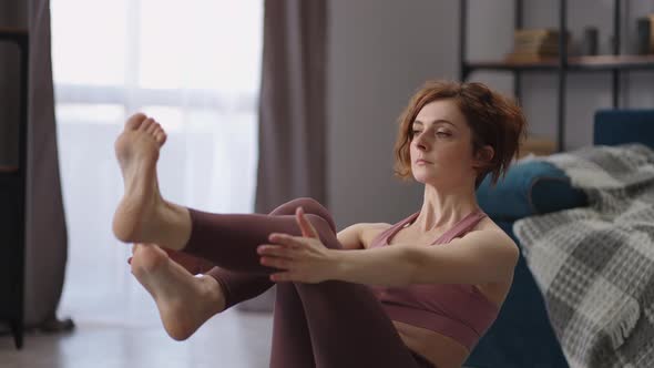 Adult Sporty Lady is Practicing Yoga at Home Doing Paripurna Navasana Boat Pose on Floor in alt