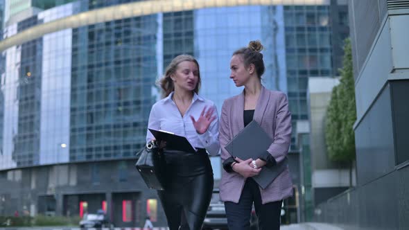 Two young women discussing business on the go after work alt