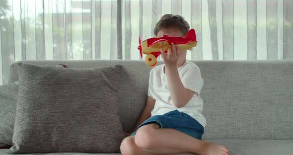 A Cute Little Preschooler Boy Playing at Home on the Sofa with a Toy Airplane a Cute Little Son alt