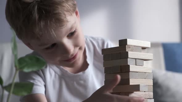 Boy is Playing in Board Game with Wooden Tower Together at Home