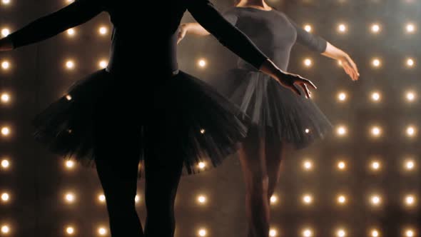Silhouette of Two Ballerinas in Black Tutu is Dancing Ballet in the Dark Studio