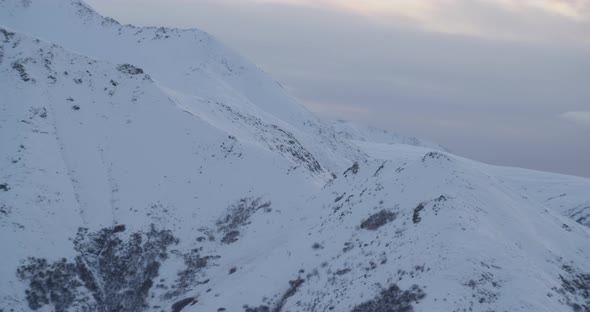 Zoom in on on Alaska State Trooper helicopter flying helicopter in front of mountains, drone aerial  alt