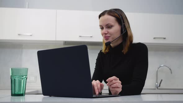 A Young Female Call Center Employee Talks to a Client Sitting at Home