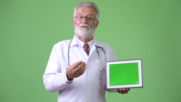 Handsome Senior Bearded Man Doctor Against Green Background alt