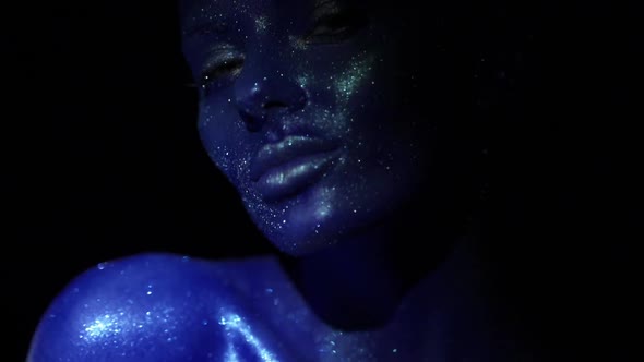 Portrait of Beautiful Woman with Blue Sparkles on Her Face