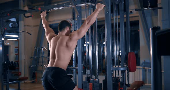 Bodybuilder Doing Exercise on the Simulator in the Gym alt