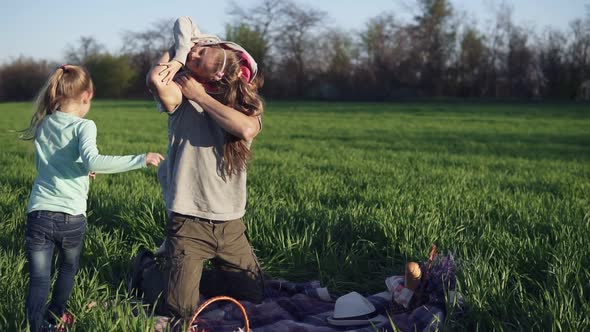 A Young Parent Plays with His Grownup Daughters in a Meadow on a Litter alt