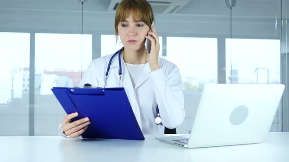 Doctor Holding Medical Reports and Talking on Phone alt