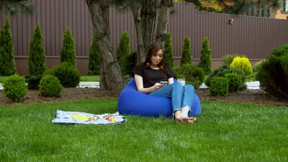 Young Woman Using Smartphone in Garden