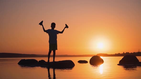A Happy Child is Playing with a Paper Airplane at Sunset alt