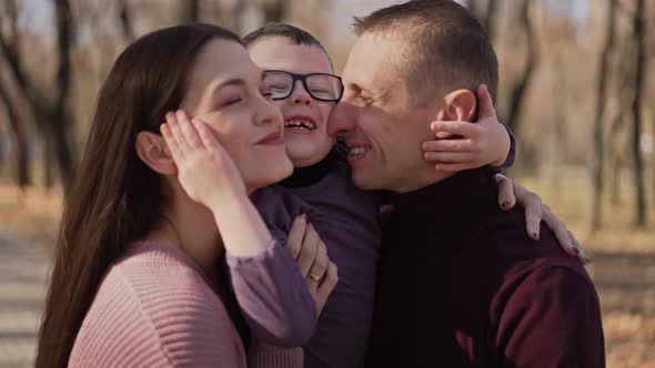 Mom and Dad Hug and Kiss Their Son alt