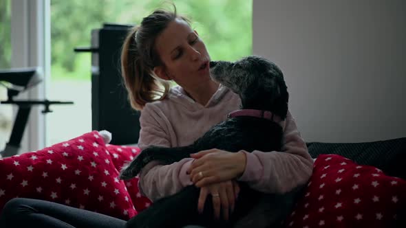 Young Woman On A Couch  Cuddling With Her Dog