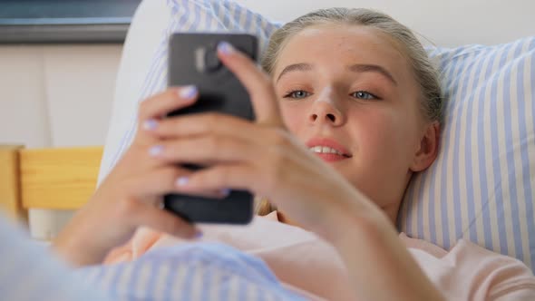 Happy Girl with Smartphone in Bed at Home alt