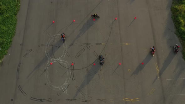 top down wide aerial view of a group of riders practicing on an advanced motorcycle training slalom alt